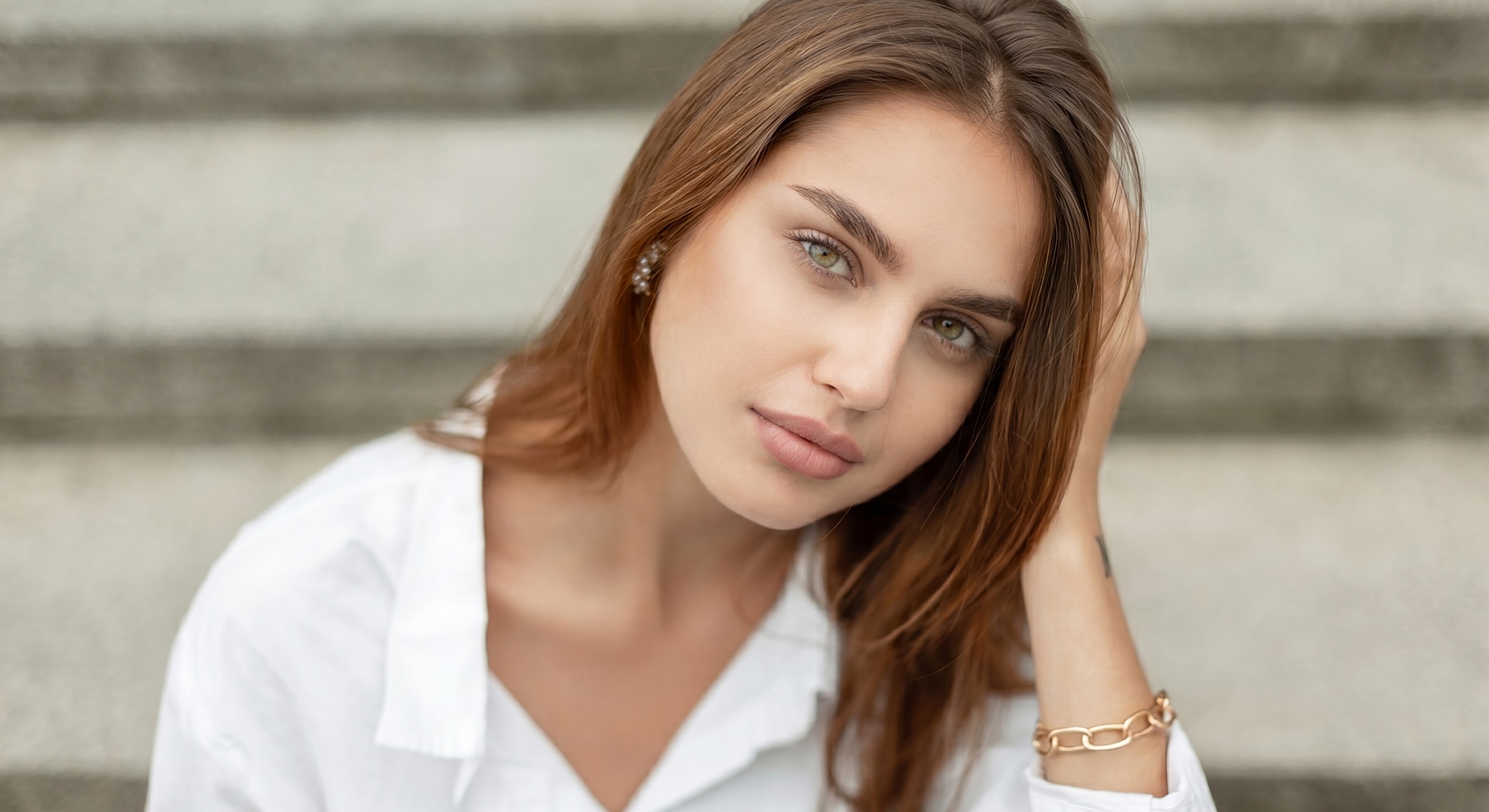 Paramus LED facial treatment model with long hair sitting on stairs.